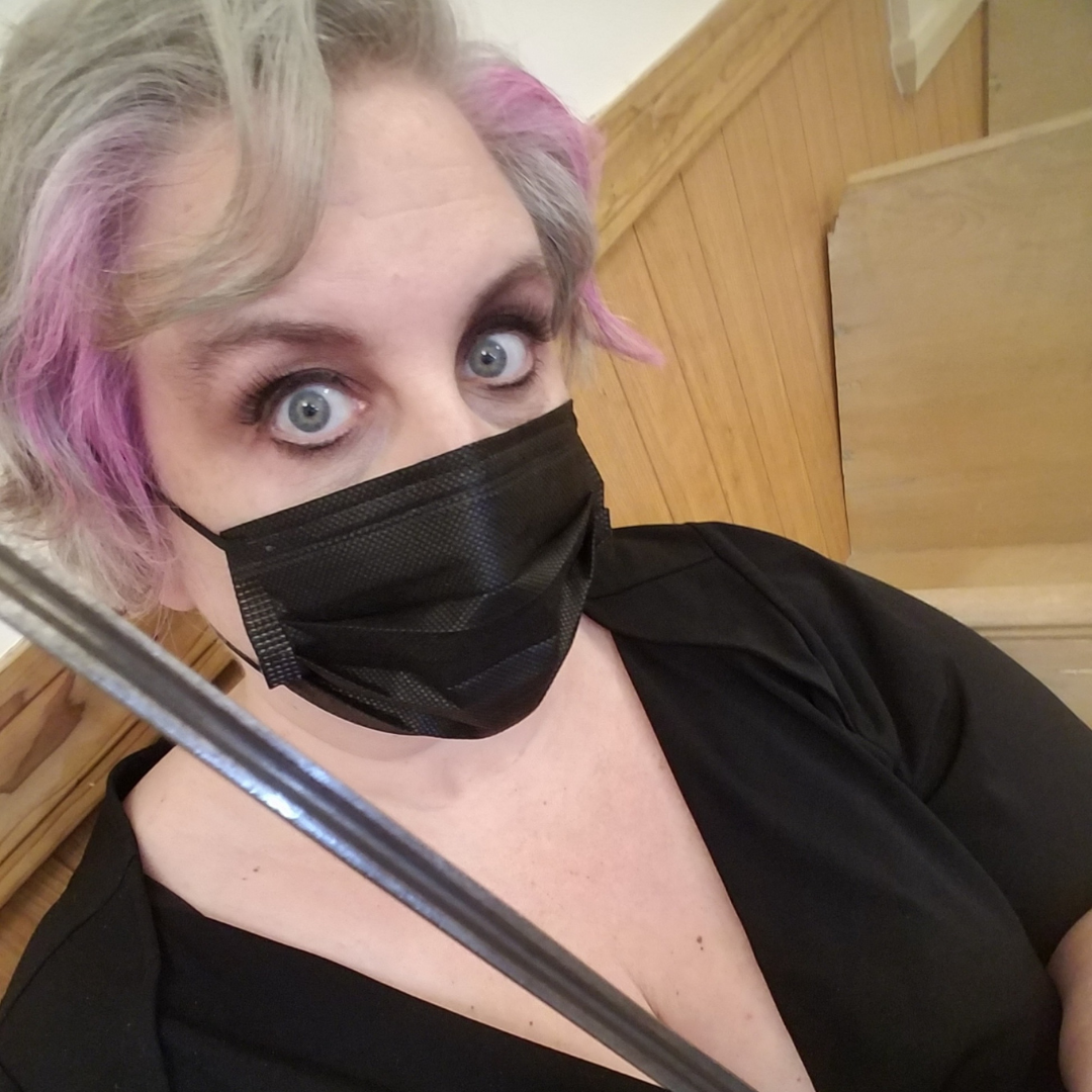 Jessica Ellis-Wilson looking at the camera wearing a black shirt, black face mask and holding a sword